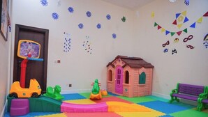 A playroom with a playhouse, a basketball hoop, and colorful mats. - Al Mada Arabia Hotel (Jizan)