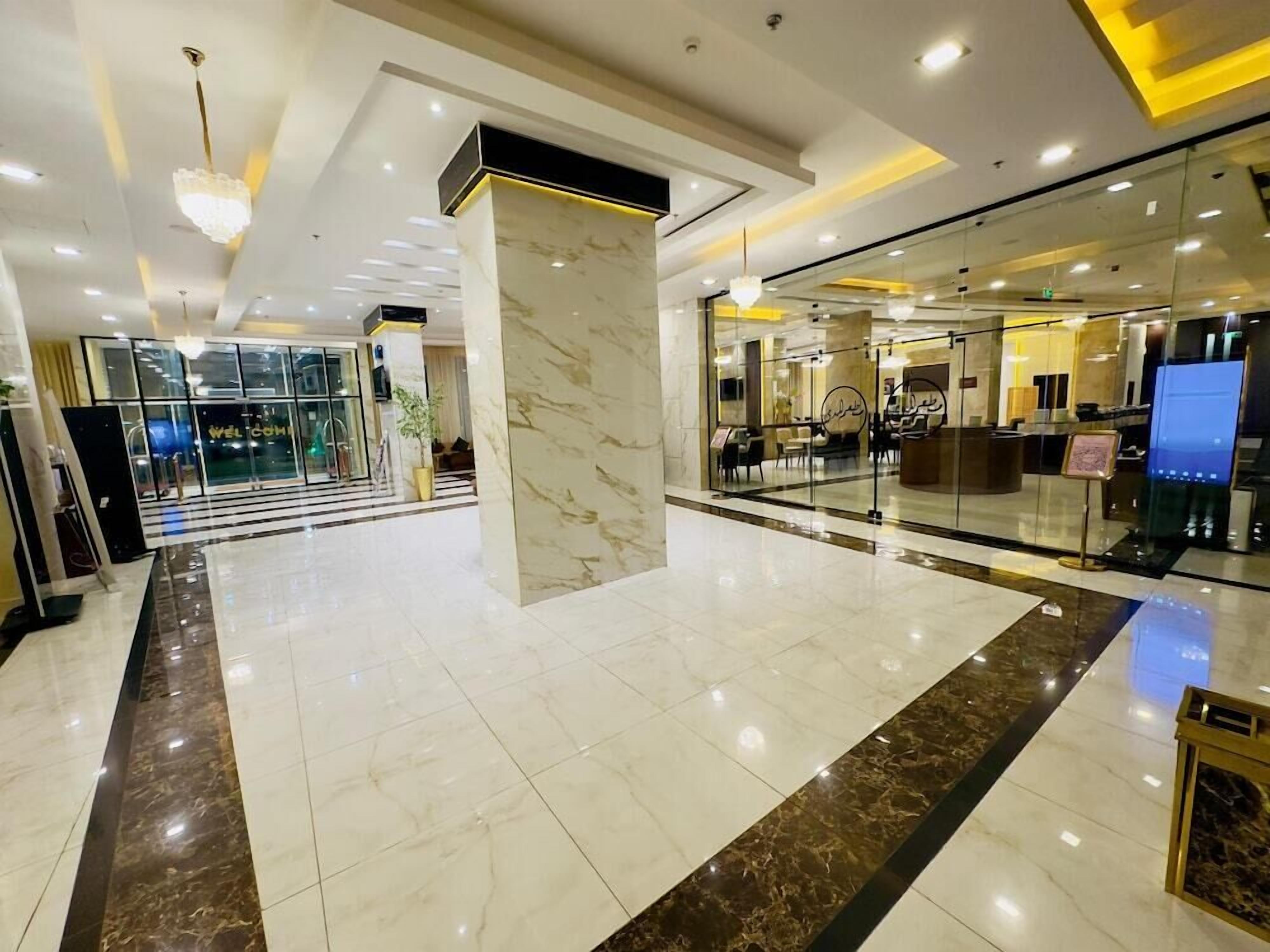 A hotel lobby with a marble floor, a reception desk, and a glass partition.