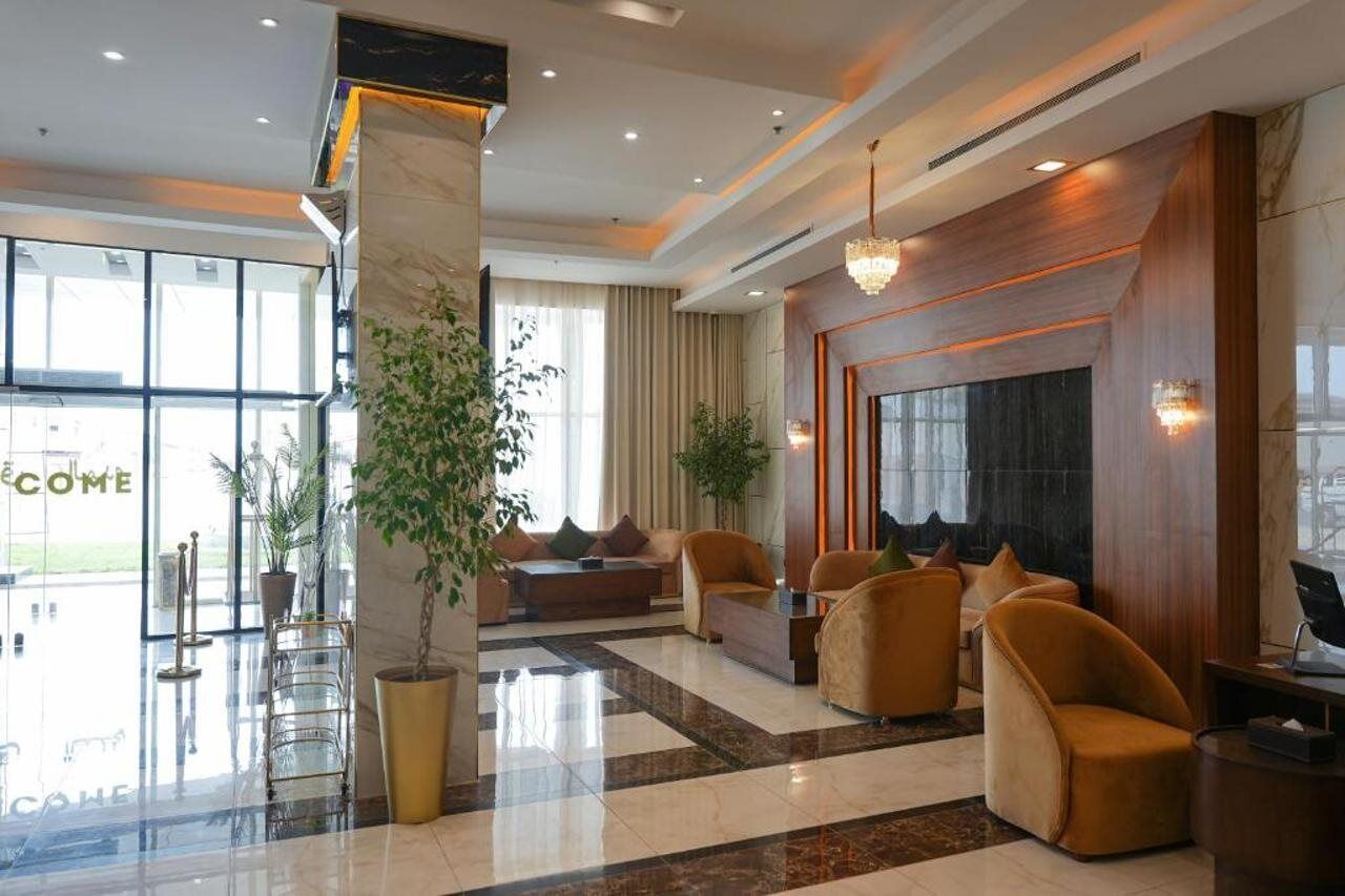 A hotel lobby with a reception desk, seating area, and large windows.