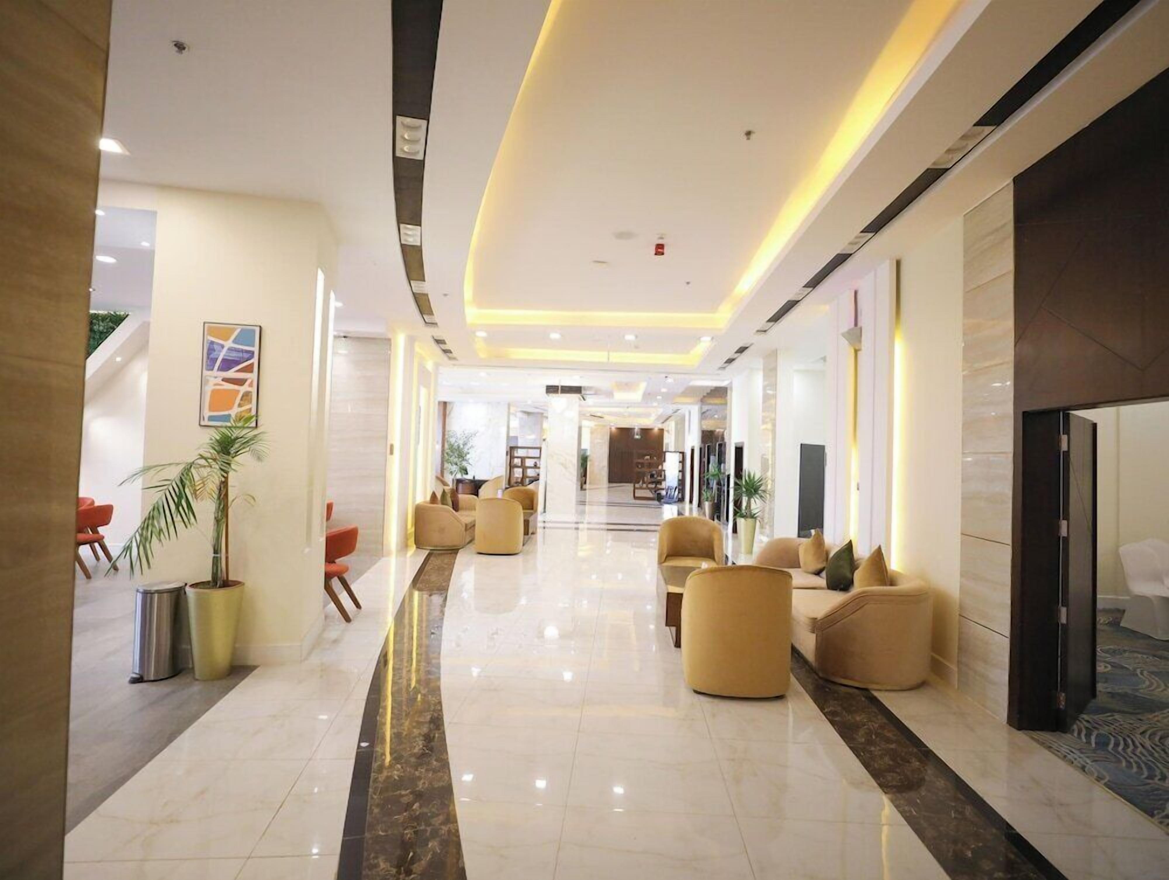 A hotel lobby with a marble floor, seating areas, and a reception desk.