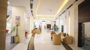 A hotel lobby with a marble floor, seating areas, and a reception desk.