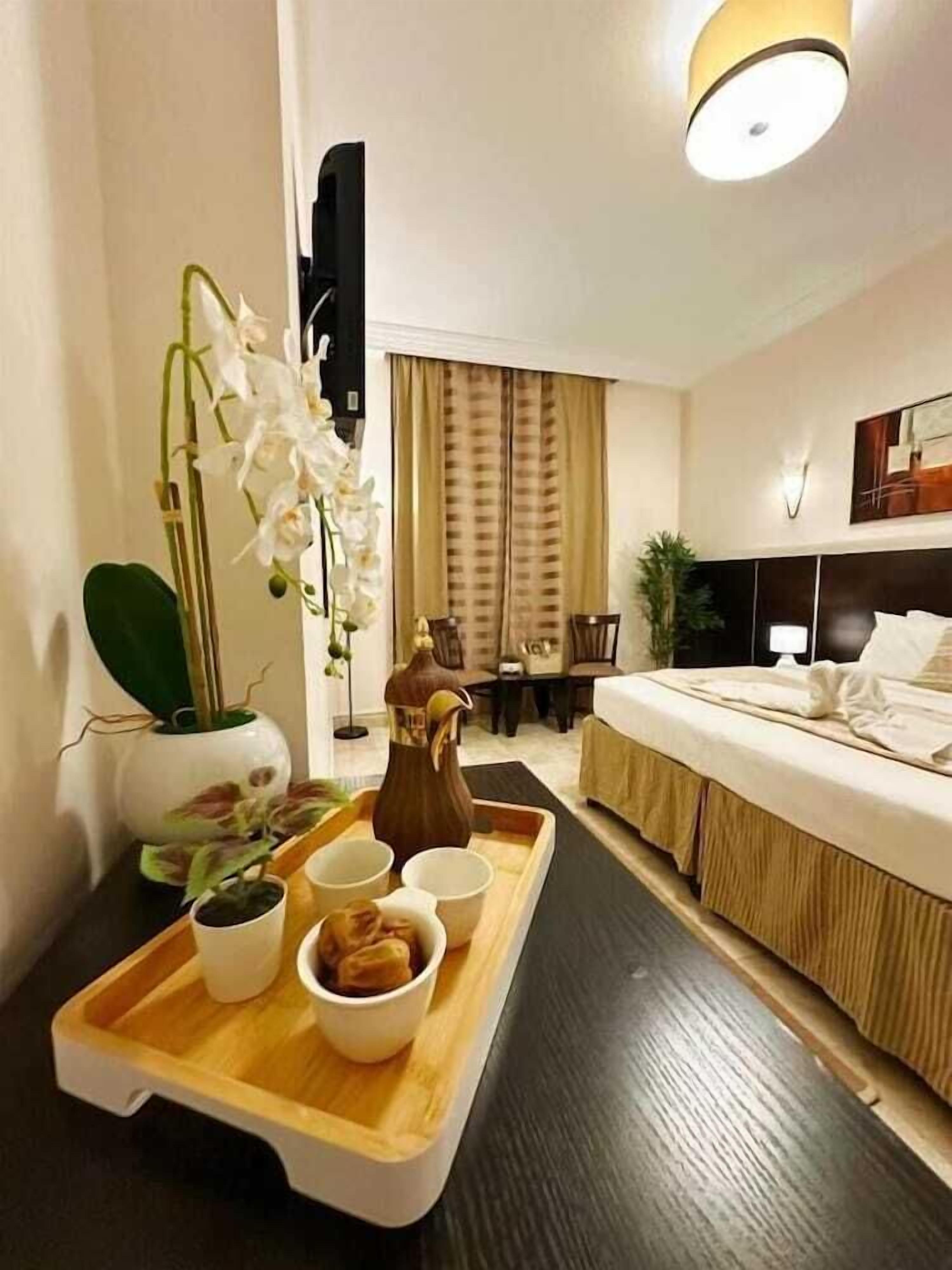 Ein Hotelzimmer mit Bett, Nachttisch und Tablett mit Speisen und Getränken.