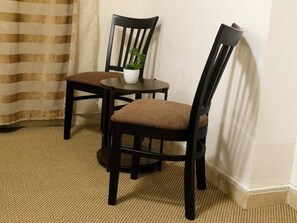 A room with two dark wooden chairs, a small round table, and a potted plant. - Hussein Hassan Ali Bayari Hotel (Makkah)