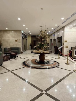 A lobby with a reception desk, a seating area with a sofa and armchairs, and a decorative vase with flowers. - Hussein Hassan Ali Bayari Hotel (Makkah)