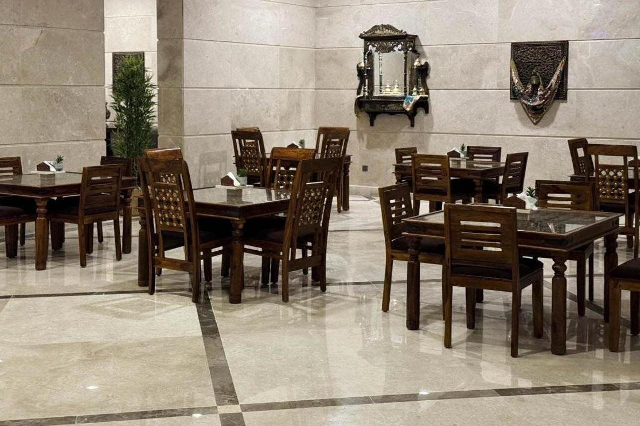 Une salle à manger élégante, avec un sol en marbre, des tables et des chaises en bois, et des miroirs décoratifs sur les murs.