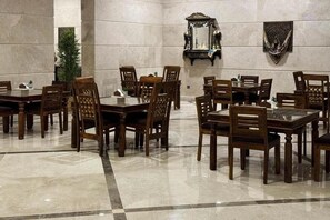 A formal dining area with marble flooring, wooden tables and chairs, and decorative wall mirrors. - Hussein Hassan Ali Bayari Hotel (Makkah)
