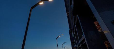 A long, empty pedestrian walkway with street lamps and a building on one side.