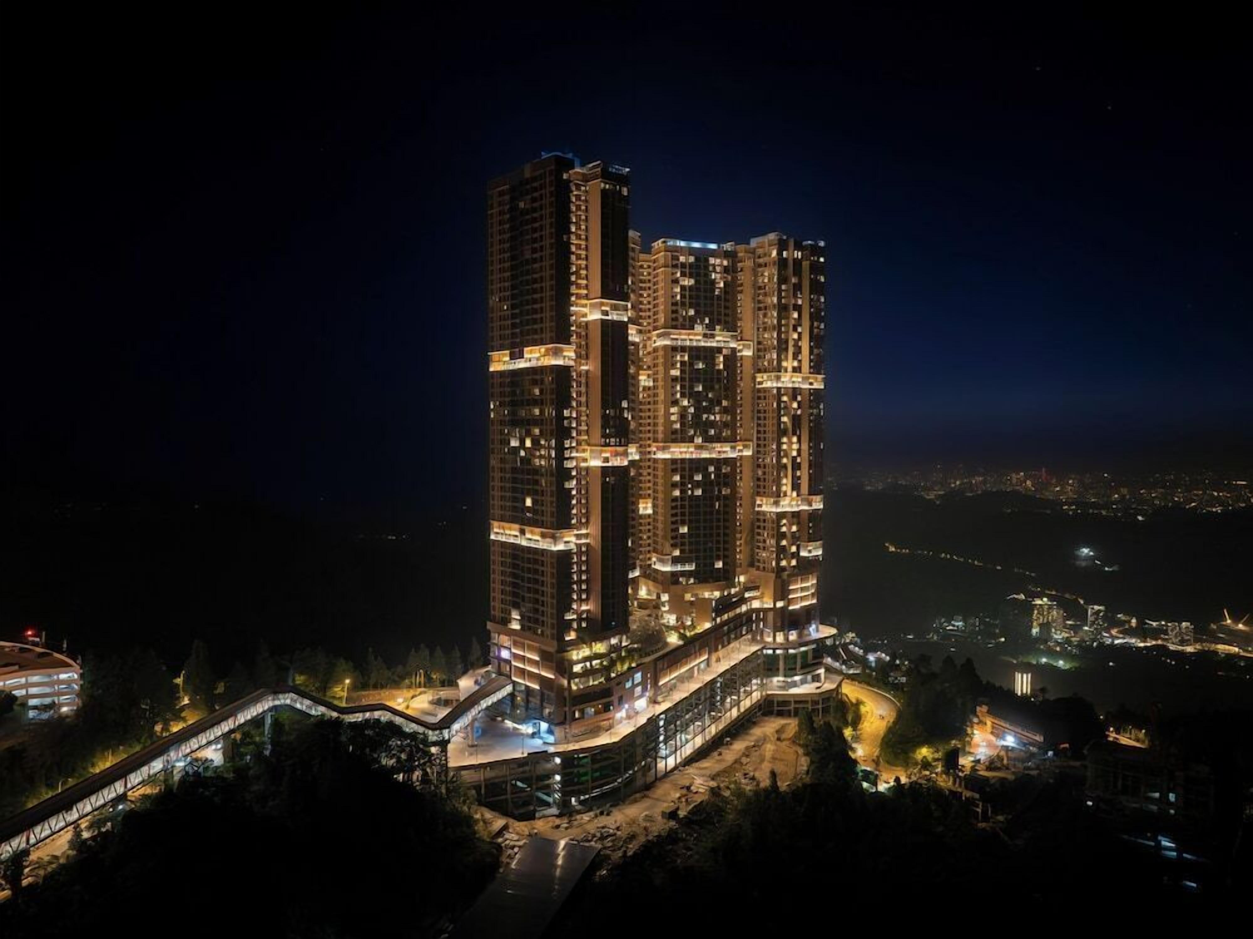 A high-rise building with multiple floors, surrounded by a well-lit area and a bridge.