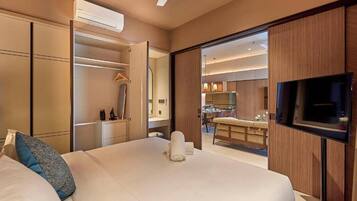 A hotel room with a bed, a TV, a wardrobe, and a view into the kitchen area.