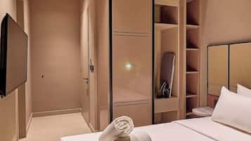 A hotel room with a bed, a television, a wardrobe, and an air conditioning unit.