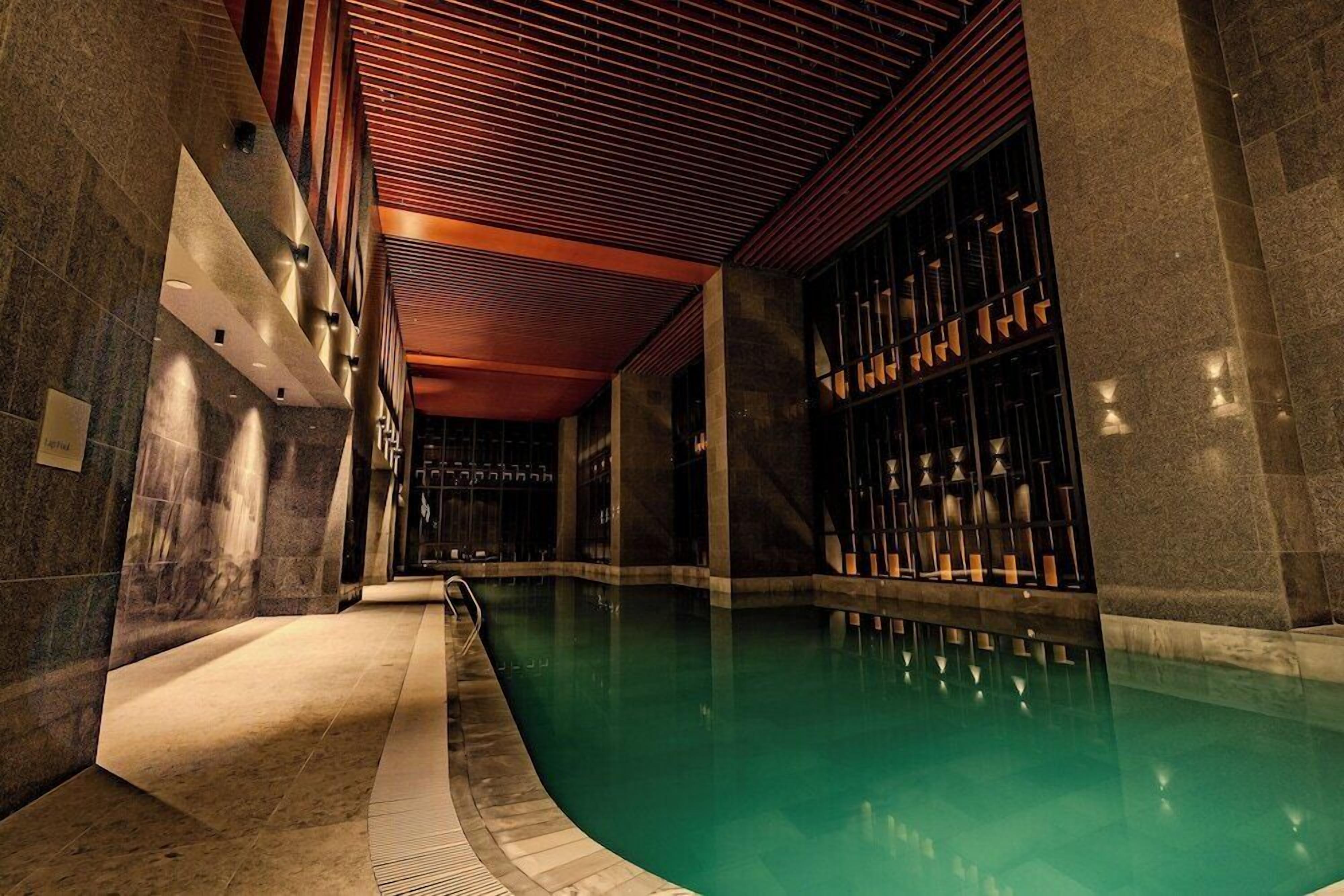 A swimming pool with a curved edge, surrounded by stone walls and a wooden ceiling.