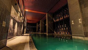 A swimming pool with a curved edge, surrounded by stone walls and a wooden ceiling.