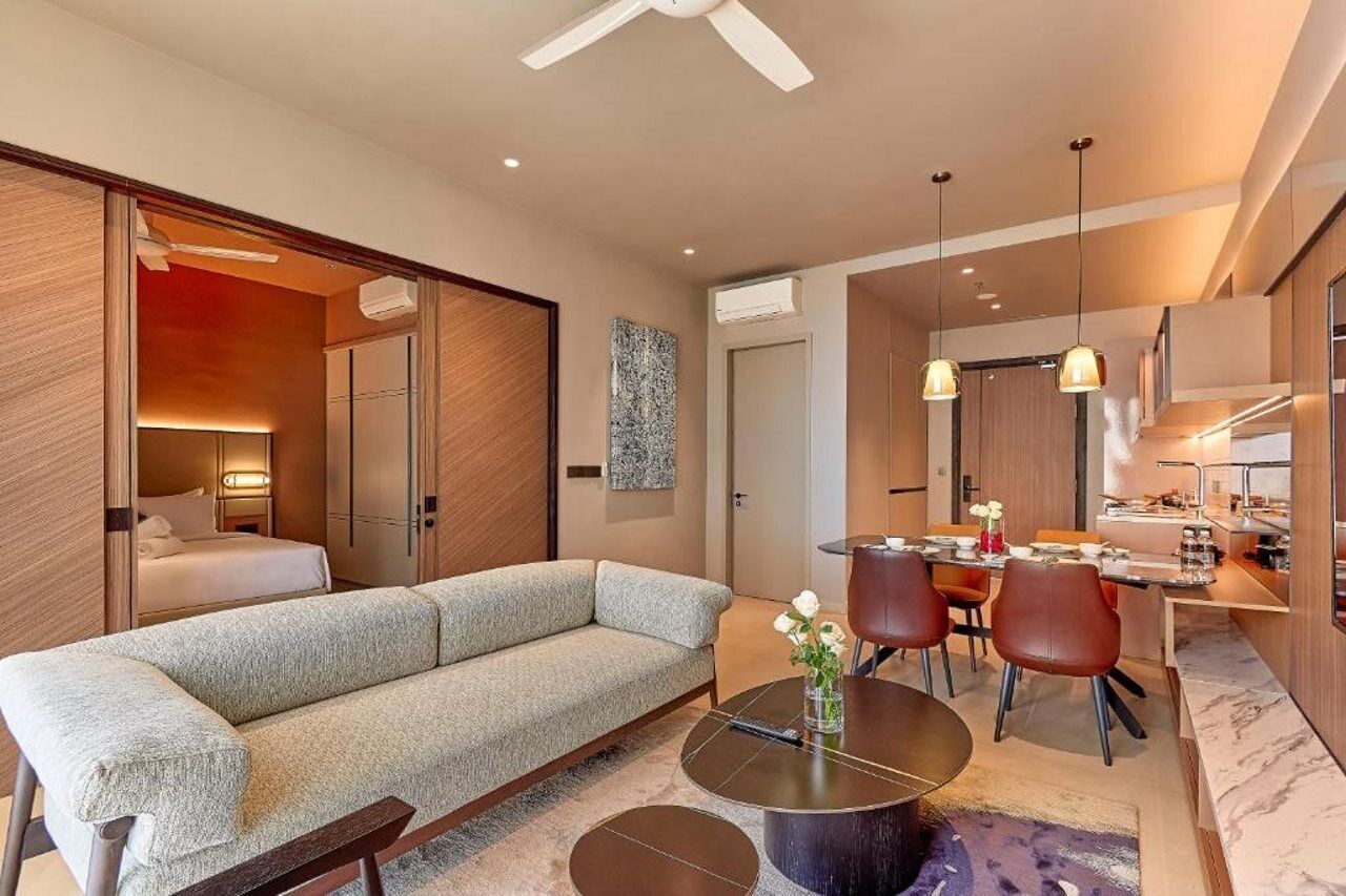 A modern living room with a sofa, dining table, and chairs, a ceiling fan, and a kitchen area with a dining table and chairs.