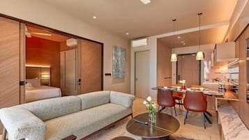 A modern living room with a sofa, dining table, and chairs, a ceiling fan, and a kitchen area with a dining table and chairs.