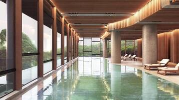 A swimming pool with a clear view of the outdoors, surrounded by lounge chairs and a wooden ceiling structure.