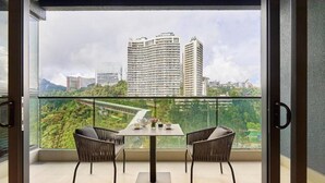 A balcony with a table and two chairs, offering a view of a cityscape with high-rise buildings and greenery. - Antara Genting Highlands by Sleeping Lion (Genting Highlands)