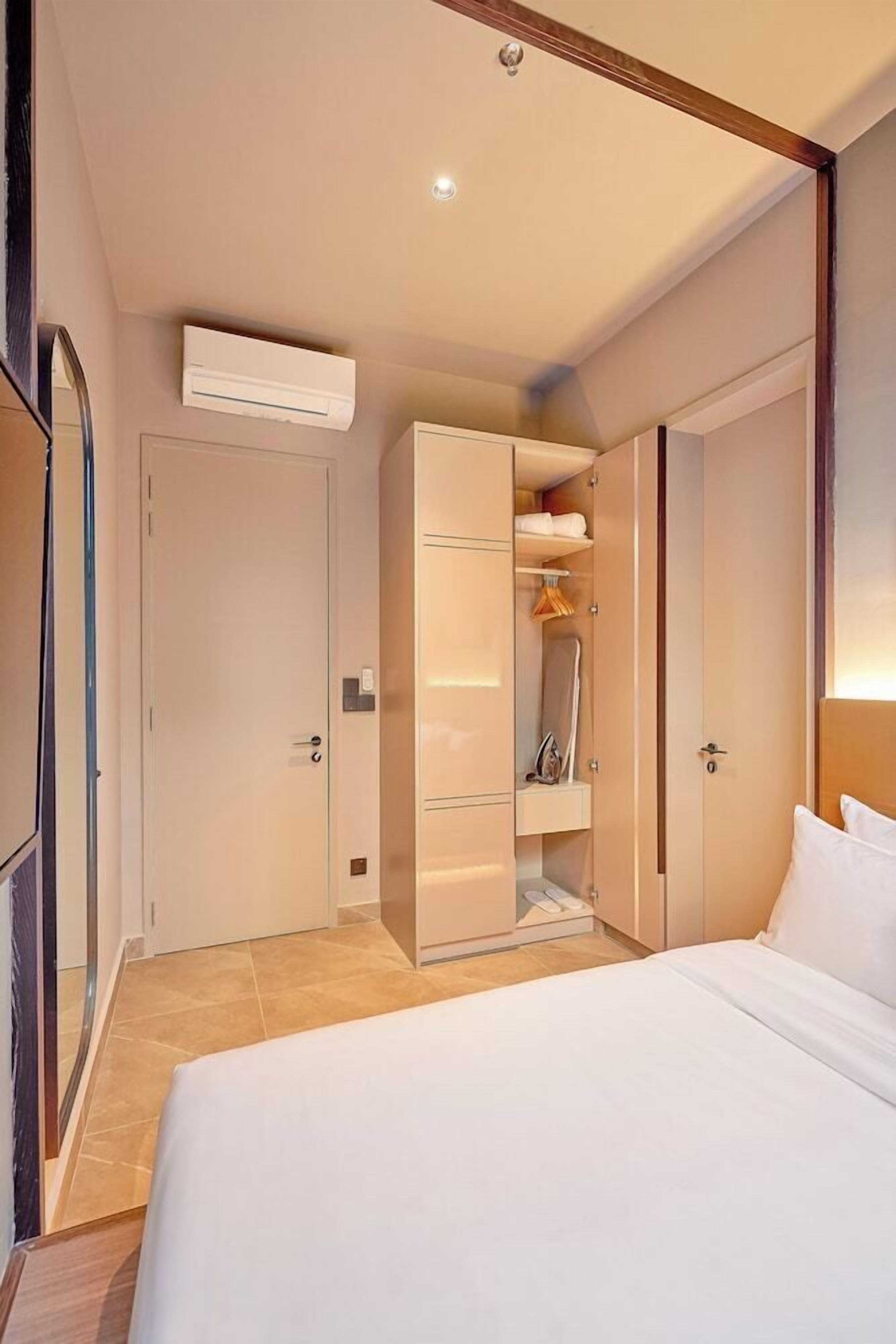 A hotel room with a bed, a wardrobe, and an air conditioning unit.