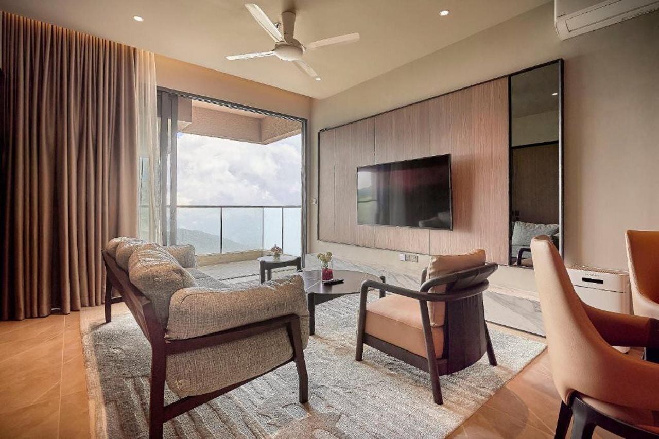 A modern living room with a sofa, armchairs, a coffee table, and a flat-screen TV mounted on the wall.