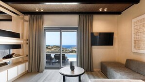 A modern hotel room with a large window, a flat-screen TV, a sofa, a small table, and a built-in shelf. - Maximus Mykonos Adults Only (Mykonos)