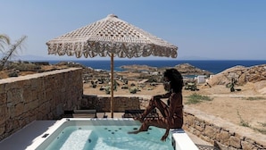 A person sitting in a hot tub with a view of the sea and landscape. - Maximus Mykonos Adults Only (Mykonos)