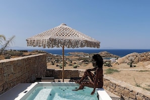 En person sidder i en jacuzzi med udsigt til havet og landskabet.