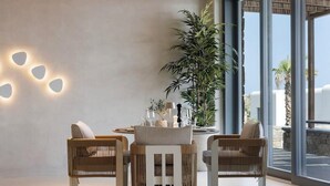 A modern interior with a round table, wicker chairs, and a large potted plant. - Maximus Mykonos Adults Only (Mykonos)