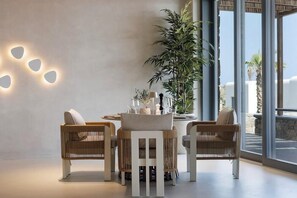 Et moderne interiør med et rundt bord, fletstole og en stor stueplante.
