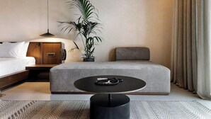 A modern hotel room with a bed, a sofa, a round table, and a potted plant. - Maximus Mykonos Adults Only (Mykonos)