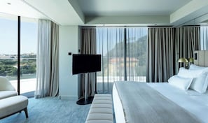 A modern hotel room with a large bed, a flat-screen TV, and a view of the cityscape. - Altis Porto (Porto)