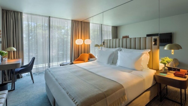 A modern hotel room with a large bed, a desk, and a chair. - Altis Porto (Porto)