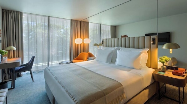 A modern hotel room with a large bed, a desk, and a chair. - Altis Porto (Porto)