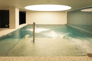Un área de spa con un jacuzzi, un tragaluz circular y una pared con azulejos.