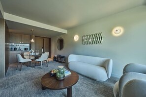 Una sala de estar moderna con un sofá, sillas, una mesa de centro y una cocina al fondo.