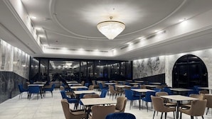 A spacious dining area with multiple tables and chairs, a large chandelier, and marble walls. - OYO 687 Sunday Jeddah Hotel (Jeddah)