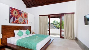 Una habitación de hotel con una cama grande, cabecera de madera, un cuadro en la pared y vistas a través de una puerta.