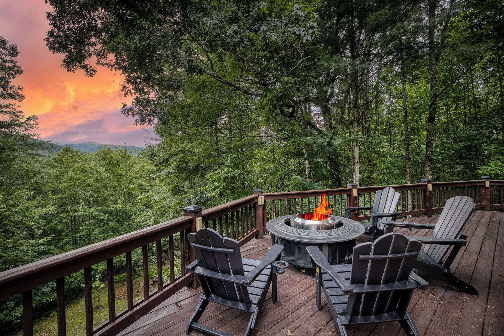 Eine Terrasse mit Feuerstelle, Stühlen und Blick auf eine bewaldete Landschaft.