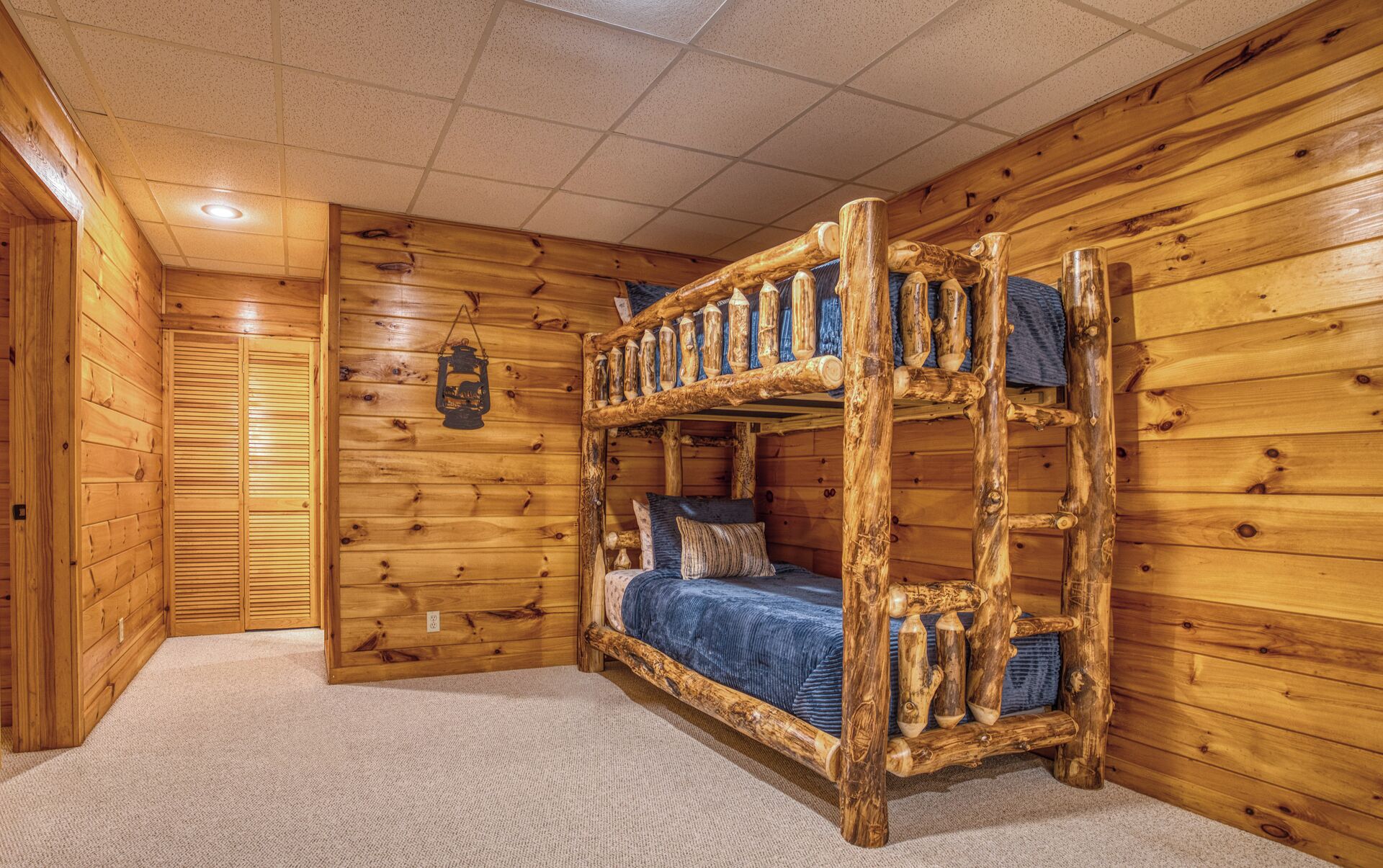 A bunk bed with a wooden ladder, a hanging lantern, and a closet with sliding doors.