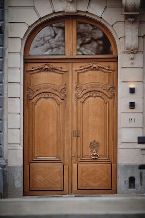 A double wooden door with intricate carvings and a glass window above it.