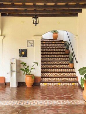 A staircase with patterned tiles, a water dispenser, and potted plants. - Iraola Hotel Boutique (Salta)
