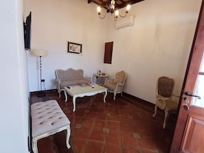 Un salon comprenant un canapé, une table basse, un fauteuil et un téléviseur fixé au mur.