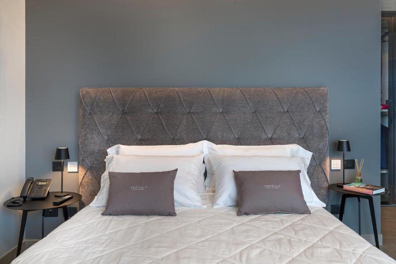 Camera d'albergo con un letto grande, due comodini, un telefono e una lampada su entrambi i lati.