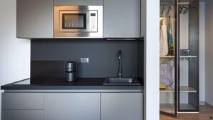 Moderni keittiö, jossa on sisäänrakennettu mikroaaltouuni, kahvinkeitin ja pesuallas.