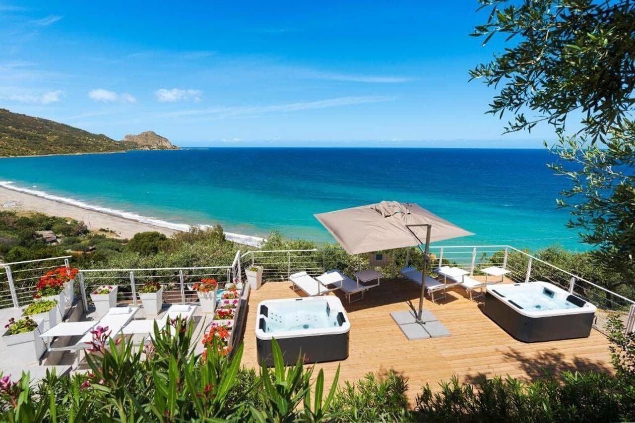 Um terraço com espreguiçadeiras, uma banheira de hidromassagem e vista para o oceano.