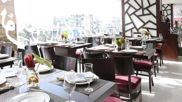 A restaurant with tables set for dining, chairs, and a decorative wall with geometric patterns. - Sedra Al Aalami Hotel (Madinah)