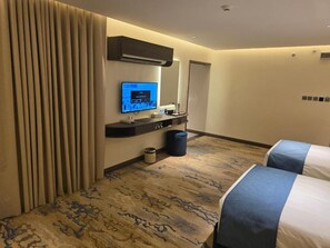 A hotel room with a bed, a television, a desk, and a mirror.