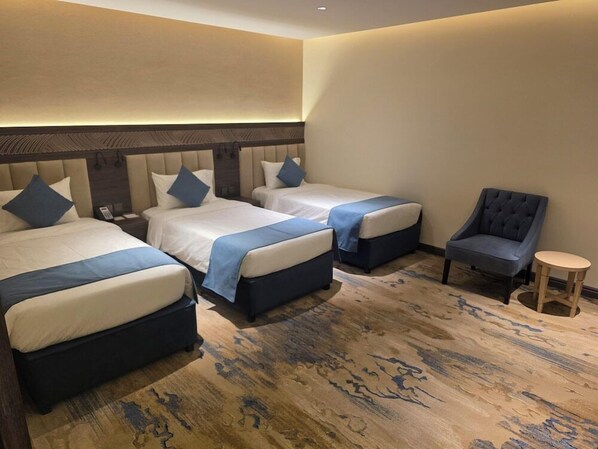 A hotel room with two beds, a chair, and a small table. - Sedra Al Aalami Hotel (Madinah)