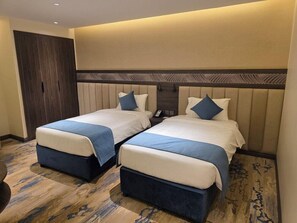 A hotel room with two beds, a wardrobe, and a carpeted floor. - Sedra Al Aalami Hotel (Madinah)