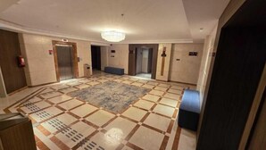 A hotel lobby with a check-in counter, elevators, a patterned carpet, and a chandelier. - Sedra Al Aalami Hotel (Madinah)