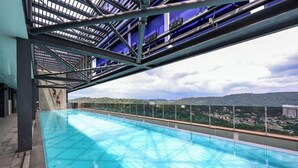 An indoor swimming pool with a view of a cityscape and hills in the background. - Mossaz Suites by Mykey Global (Kuala Lumpur)