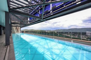 Una piscina interior con vistas a un paisaje urbano y colinas al fondo.